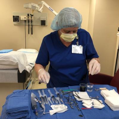 A research nurse prepares a tray of medical implements in preparation to perform a biopsy.