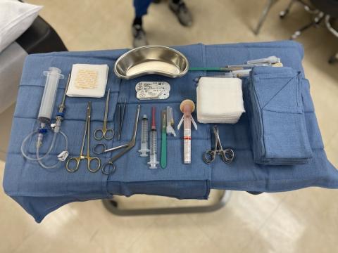 A sterile field tray of tools for a medical biopsy, such as syringes, forceps, and gauze.